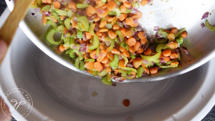 Transferring the sautéd vegetables to the slow cooker to make this Slow Cooker Curry Lentil Soup Recipe
