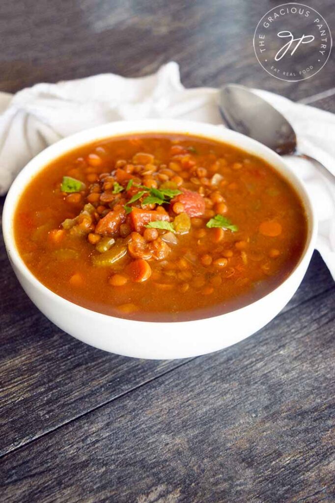 A side view of this Slow Cooker Curry Lentil Soup in a white bowl with a spoon resting at it's side.