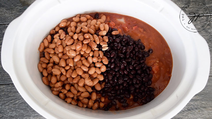 The beans layered over the sauce in the crock.