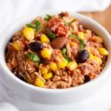 Slow Cooker Southwestern Chicken served in a white bowl with a white towel laying behind the bowl.