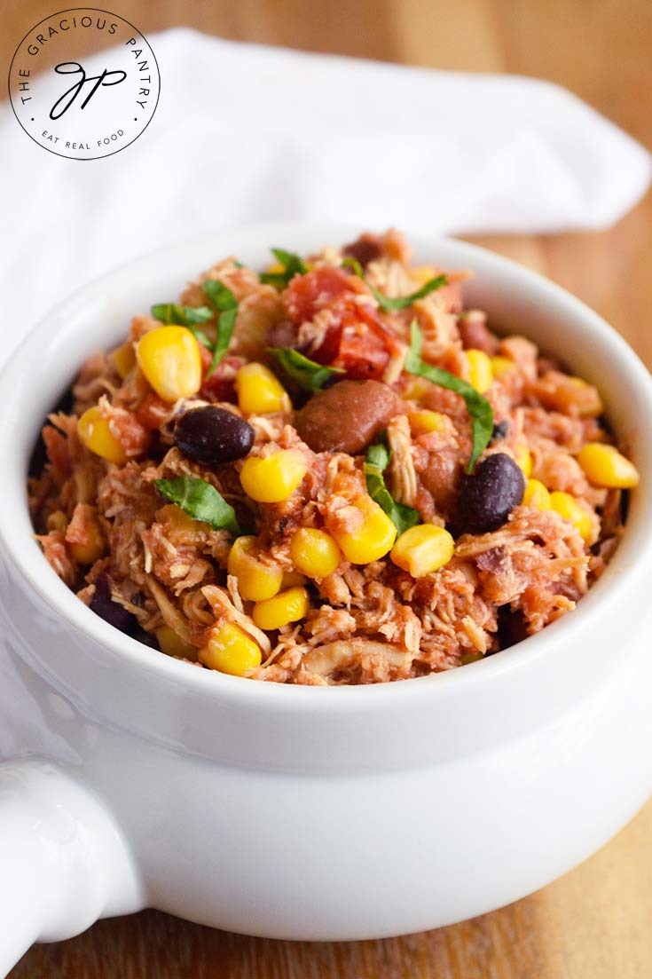 Slow Cooker Southwestern Chicken served in a white bowl with a white towel laying behind the bowl.