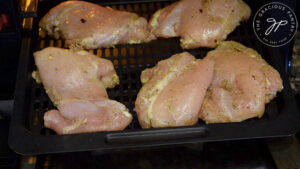 The spiced chicken thighs on the air fryer tray.