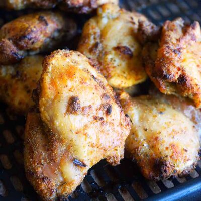 Tuscan Chicken Thighs just out of the air fryers, piled up on the air fryer tray.