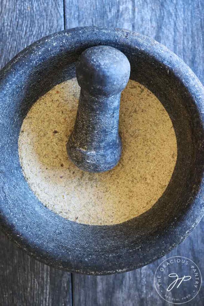 All the spices in this Tuscan Seasoning Recipe sitting mixed in a mortar with the pestle sitting on the edge.