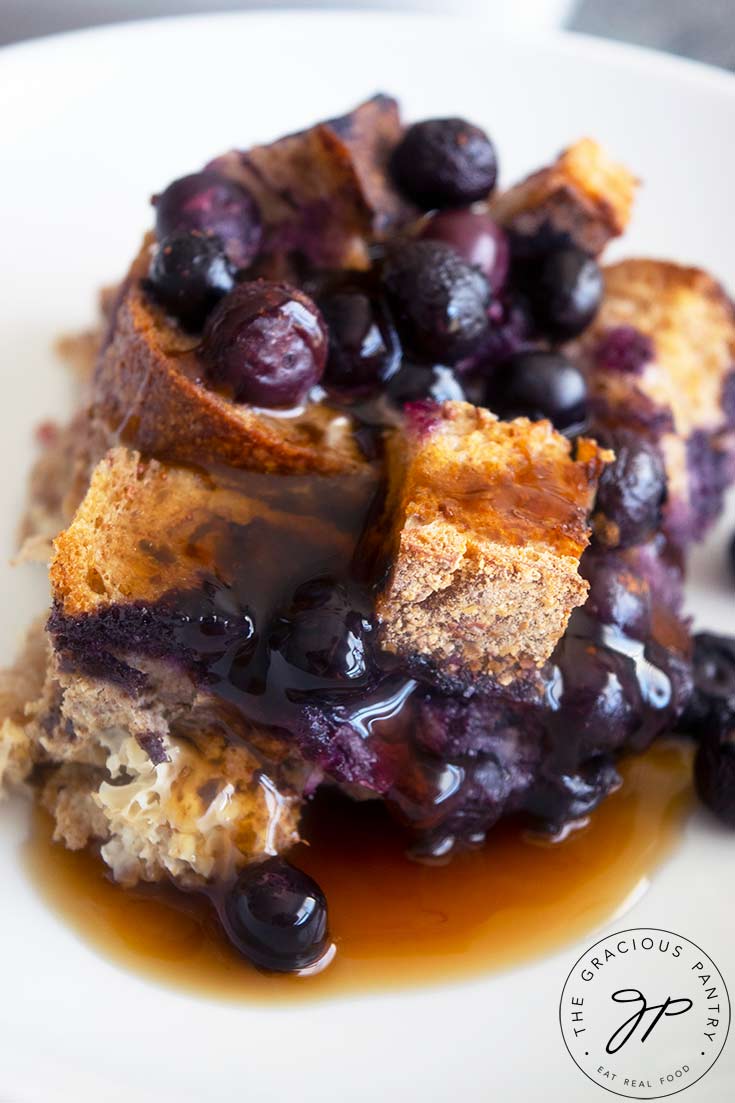 A single serving of Blueberry French Toast Casserole served with maple syrup over the top.