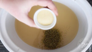 Adding the spices to the broth in the slow cookers.