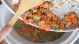 Adding sautéd veggies to the slow cooker.