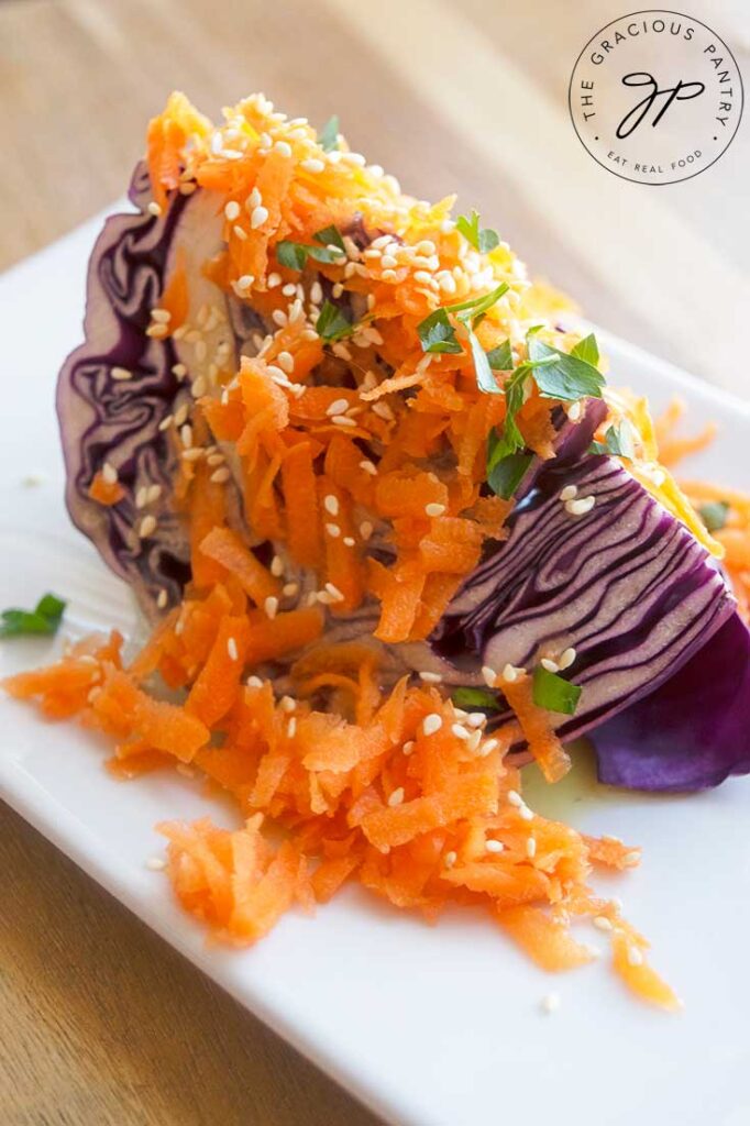 A Chinese wedge salad covered in Asian dressing, shredded carrots, fresh herbs and sesame seeds.