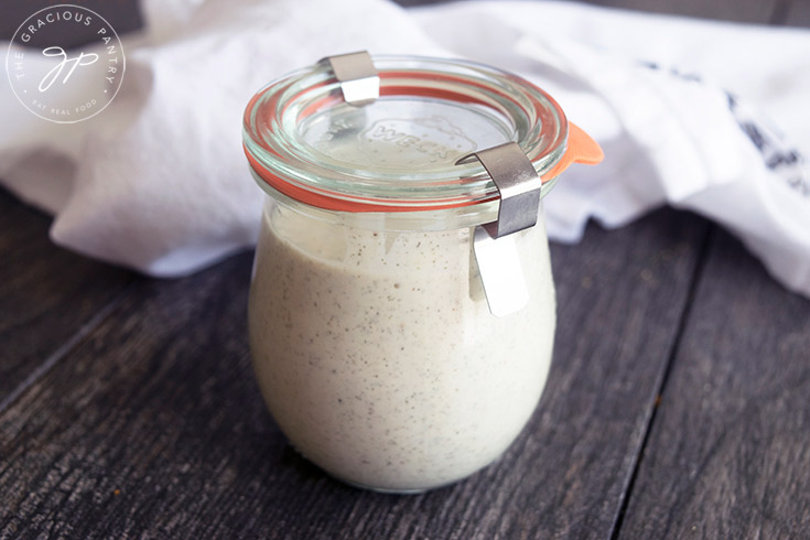 The finished jar of Dairy Free Ranch Dressing sitting on a table next to a white towel.