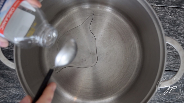 Pouring the oil into the stock pot to begin making this Healthy Italian Wedding Soup Recipe.