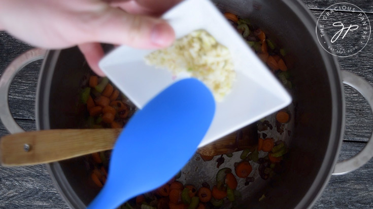 Adding garlic to the pot for this Healthy Italian Wedding Soup Recipe.