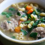 A side view of this Healthy Italian Wedding Soup in a green crock.