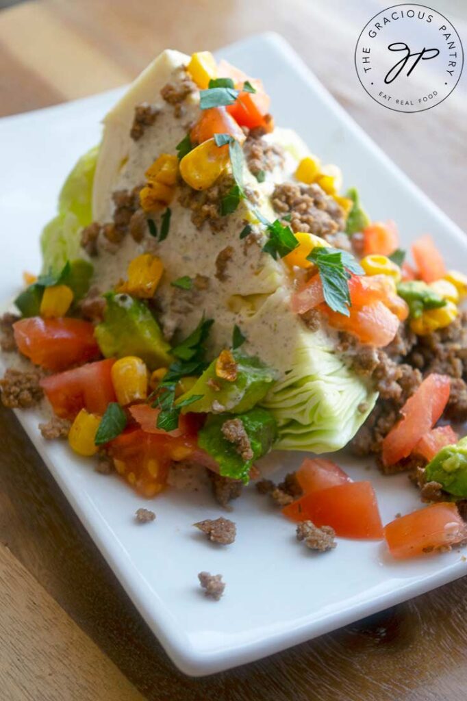 A Mexican wedge salad covered in dressing, taco meat, tomatoes, corn and avocado.