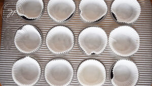 A metal muffin pan, lined with cupcake papers.