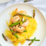 A single white, round plate set with this Shrimp And Asparagus Spaghetti Squash Spaghetti, ready to eat.