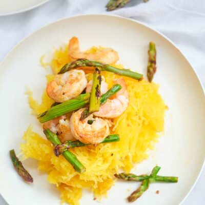 A single white, round plate set with this Shrimp And Asparagus Spaghetti Squash Spaghetti, ready to eat.