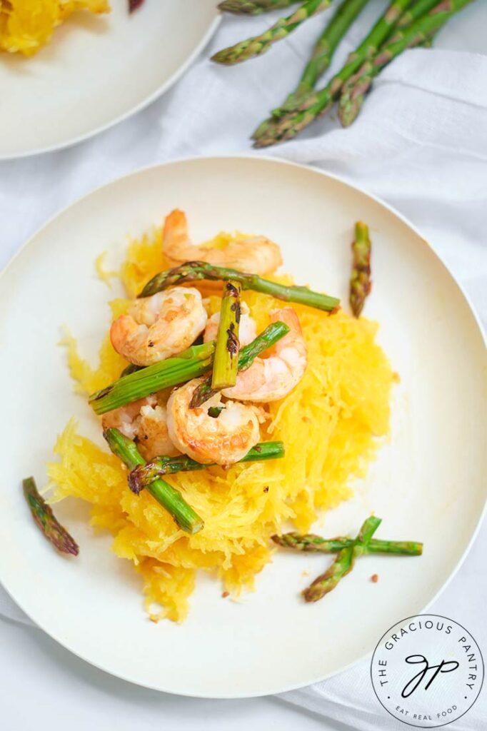 A single white, round plate set with this Shrimp And Asparagus Spaghetti Squash Spaghetti, ready to eat.