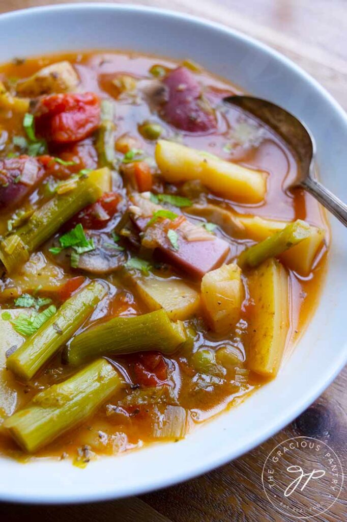 An up close view of this Spring Minestrone Soup in a white bowl with a spoon.