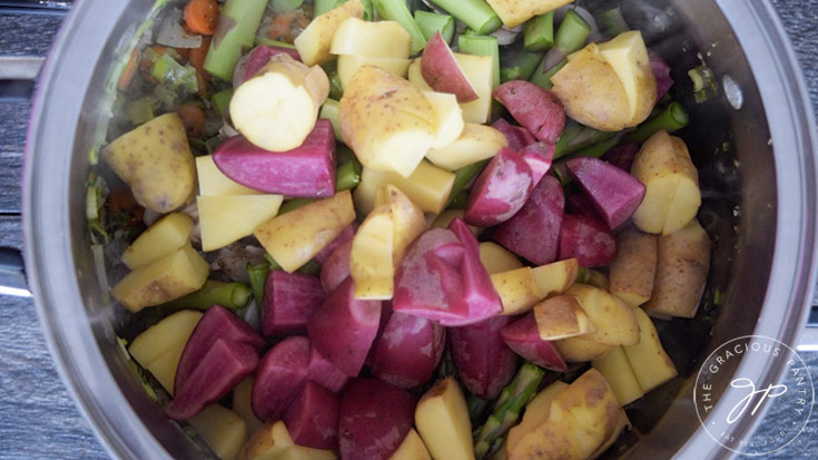 Adding the potatoes to the pot for this Spring Minestrone Soup Recipe