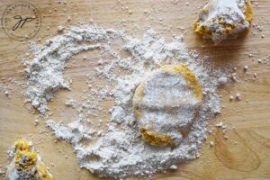 A portion of rolled Sweet Potato Flatbread dough covered in flour on a cutting board.