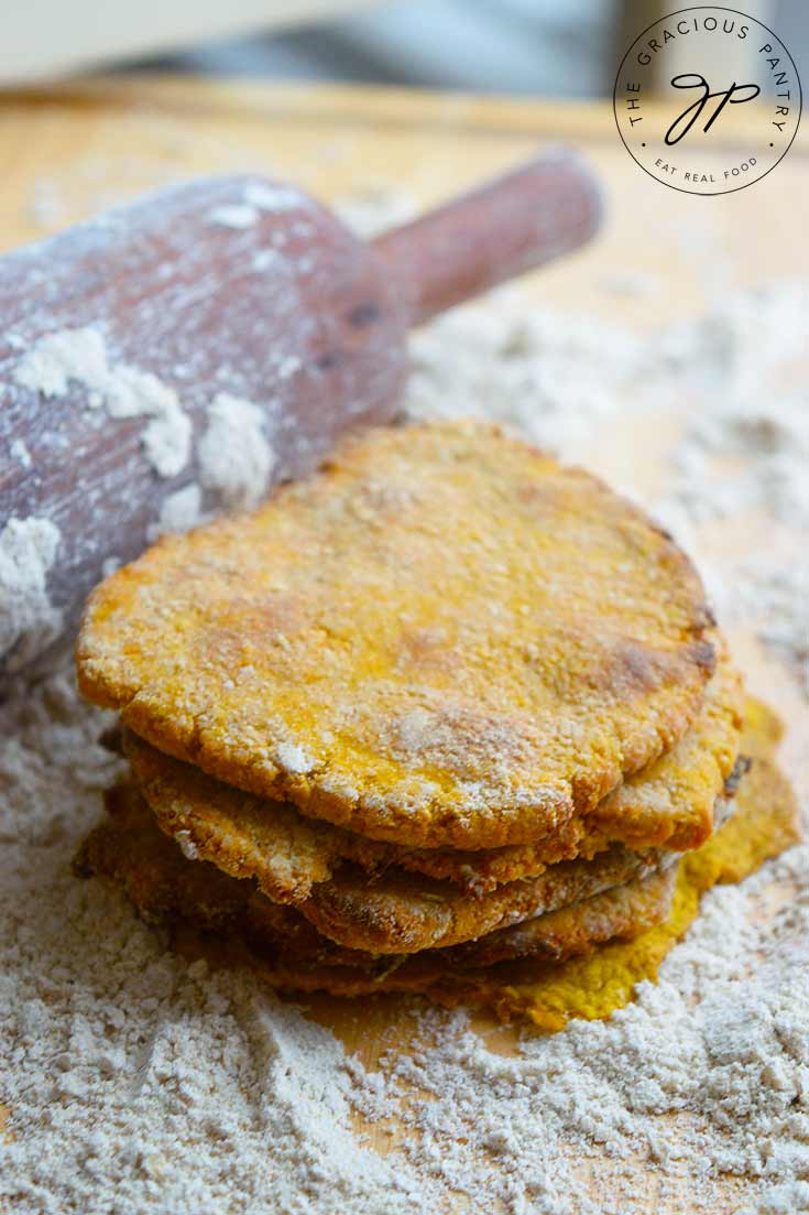 A stack of this Sweet Potato Flatbread sits on a floured surface, next to a floured rolling pin.