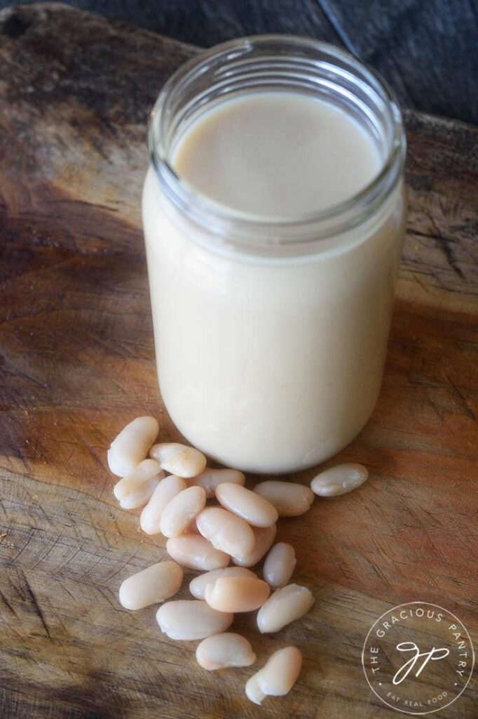 A side view of a glass jar filled with this White Bean Alfredo Sauce.
