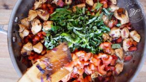 Adding the fresh herbs and tomatoes to the pan.