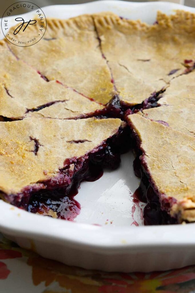 A whole Blueberry Pie with a single slice removed.