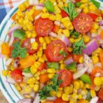 A side view of this Cajun Corn Salad Recipe in a bowl on a table.