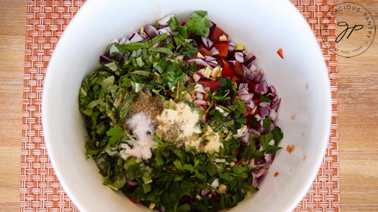 The ingredients for this Chickpea Salad Recipe sitting in a white mixing bowl, waiting to be tossed together to finish the salad.