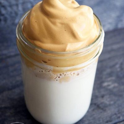 A canning jar filled with milk and topped with Dalgona Coffee.