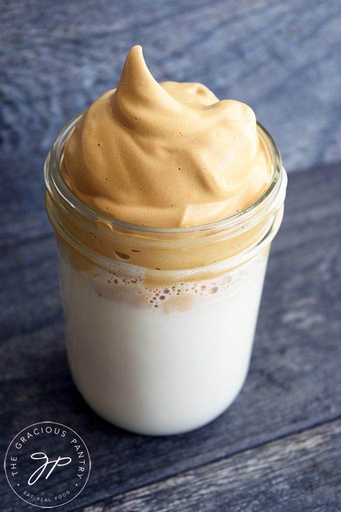 A canning jar filled with milk and topped with Dalgona Coffee.