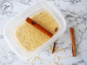 Combining the rice, water and cinnamon in a soaking container.