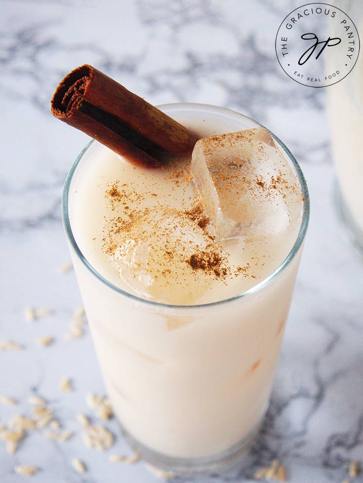 A single glass of homemade horchata with ice and a cinnamon stick.