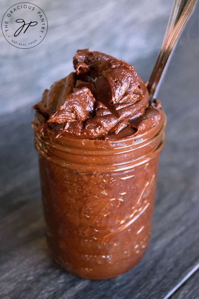 Homemade Nutella heaped into a jar with a knife, ready to scoop some out of the jar.