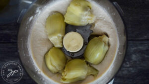 Adding the artichoke hearts to the food processor for this Healthy Spinach Artichoke Dip Recipe
