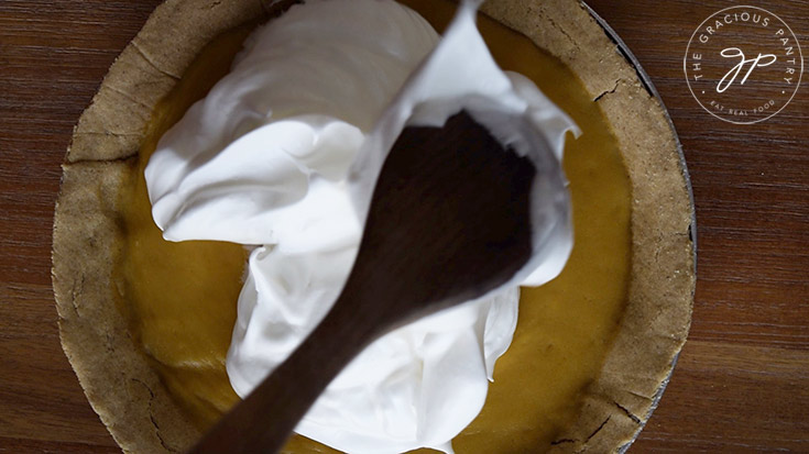 Spooning the meringue over the hot pie filling.