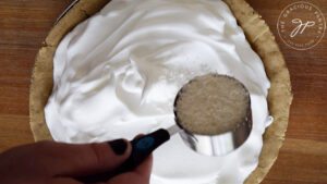 Sprinkling the shredded coconut over the meringue.