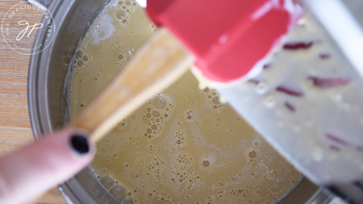 Returning the pie filling to the pot from the mixing bowl.