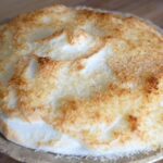 A front view of a whole, coconut meringue pie, just out of the oven.