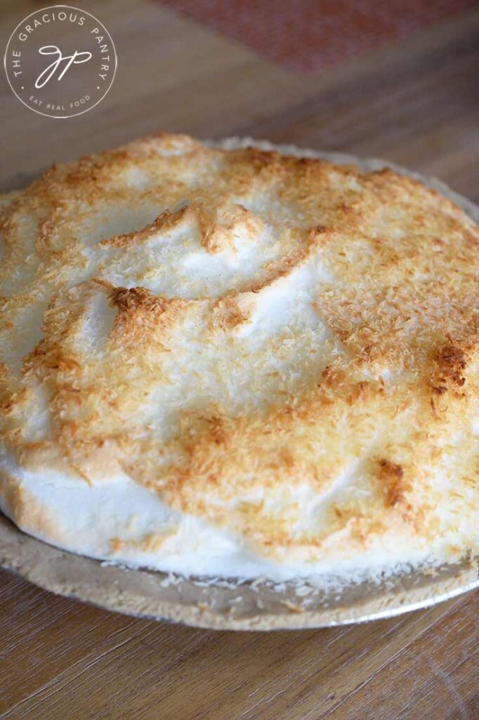 A front view of a whole, coconut meringue pie, just out of the oven.