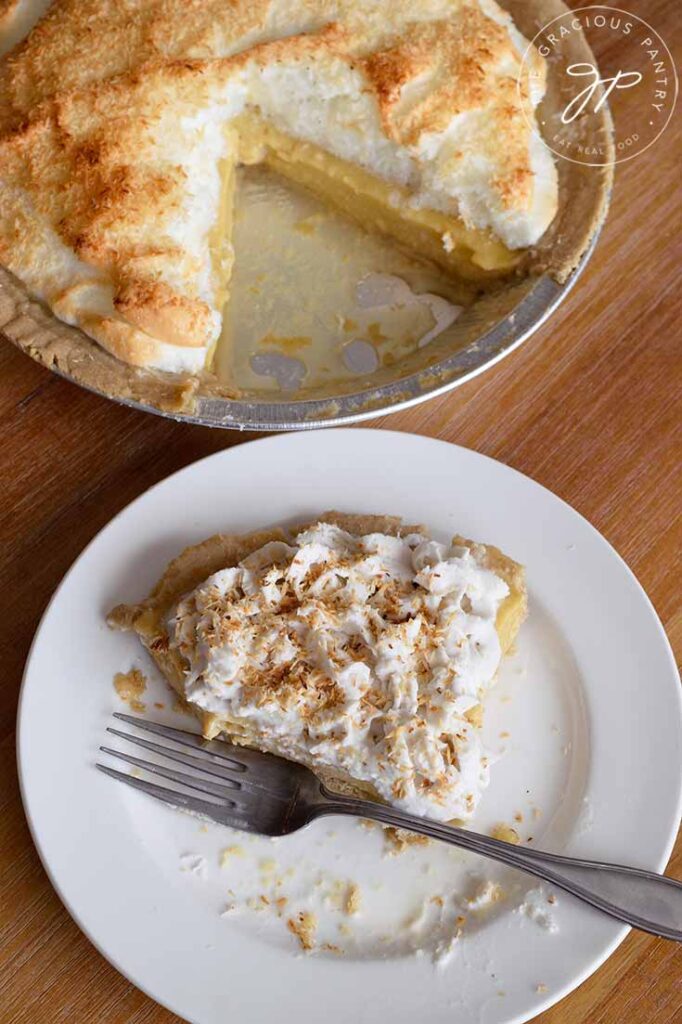 And overhead shot of a half eaten slice of coconut cream pie, with a whole coconut meringue pie sitting behind it.