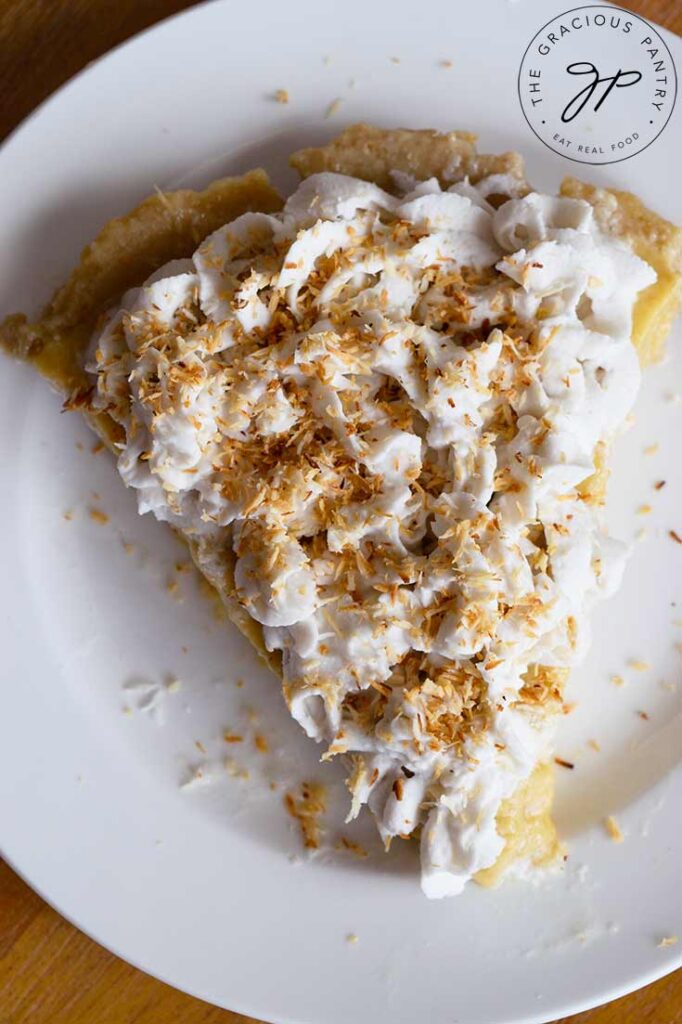 And overhead view of a single slice of coconut cream pie on a white plate.