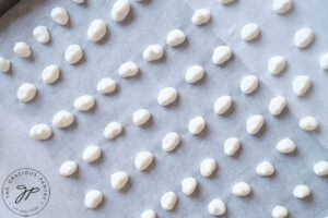 Rows of dots on a parchment lined cookie sheet.