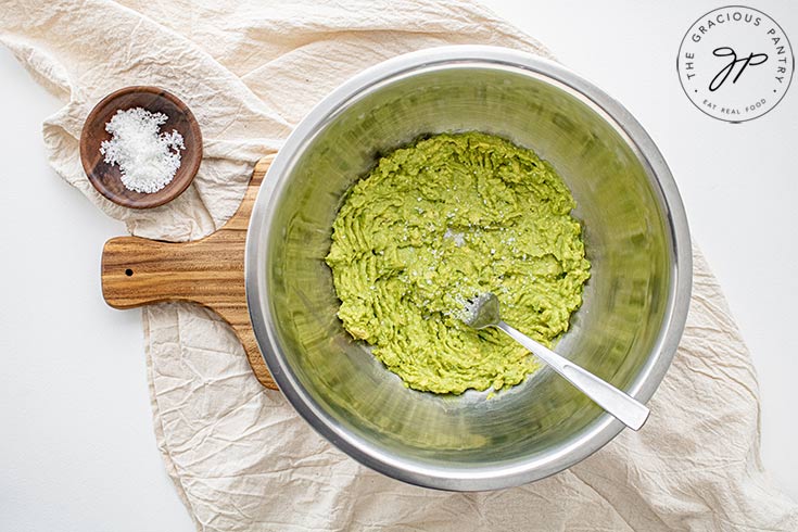 Salt added to the mashed avocado in the mixing bowl.