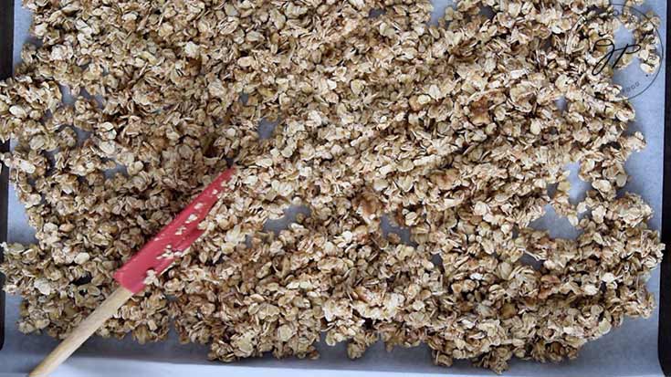 Spreading the mixed oats over the parchment lined cookie sheet.