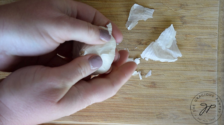 Rubbing the skins off the head of garlic for making this Roasted Garlic Vinaigrette Recipe