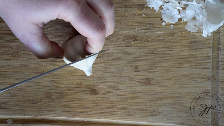 Cutting the tip off the head of garlic.