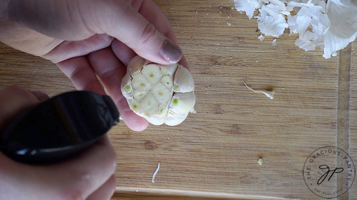 Spraying the cut head of garlic with oil.