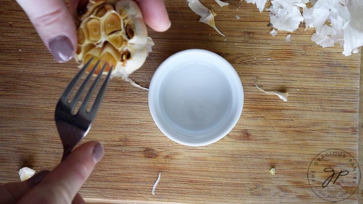 Using a fork to remove the roasted garlic cloves from the head for making this Roasted Garlic Vinaigrette Recipe